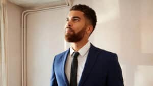 Um homem vestido com um terno azul, cabelo bem cortado e barba bem feita contesta vistoria abusiva na saída do imóvel.